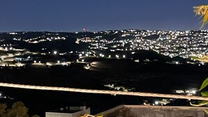 Une terrasse sur le toit offrant une vue sur le paysage urbain illuminé la nuit.
