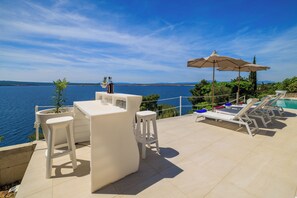 Eine Terrasse mit Bar, Sitzgelegenheiten und Blick auf einen Pool.
