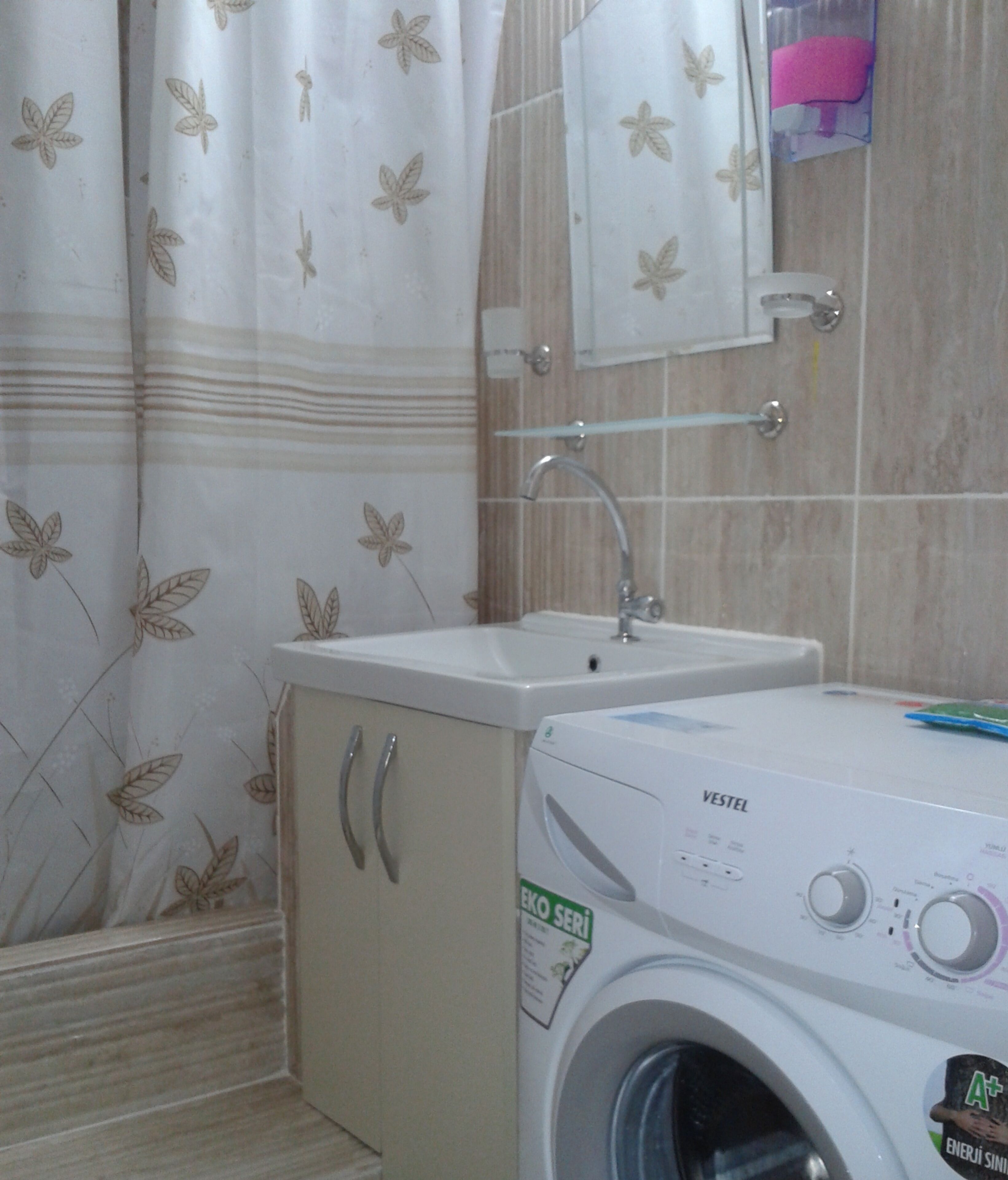 Un baño con lavadora, lavamanos y espejo.