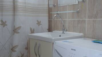Un baño con lavadora, lavamanos y espejo.