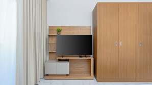 A modern room with a TV on a wooden stand, a wardrobe, and a plant. - Modern Studio with Premium Amenities (Dubai)