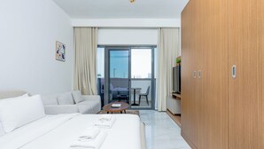 A hotel room with a bed, a sofa, a small table, a TV, and a wardrobe. - Modern Studio with Premium Amenities (Dubai)