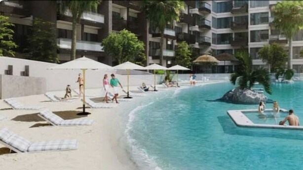 A swimming pool with lounge chairs and umbrellas, surrounded by a multi-story building with balconies. - Modern Studio with Premium Amenities (Dubai)