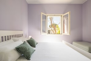 A bedroom with a bed, pillows, a bench, and a window with an open shutter. - [Stunning Villa]private garden-front beach-parking [Smart TV Wi-Fi] (Solanas)