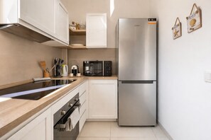 Une cuisine moderne équipée d’un réfrigérateur en acier inoxydable, d’un four à micro-ondes, d’une bouilloire et d’une machine à café.