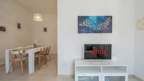 Una sala de estar moderna con comedor, televisor de pantalla plana y una obra de arte colgada en la pared.
