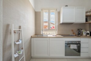 A kitchen with white cabinets, a stainless steel oven, a sink, and a window with a view of buildings. - [Stunning Villa]private garden-front beach-parking [Smart TV Wi-Fi] (Solanas)