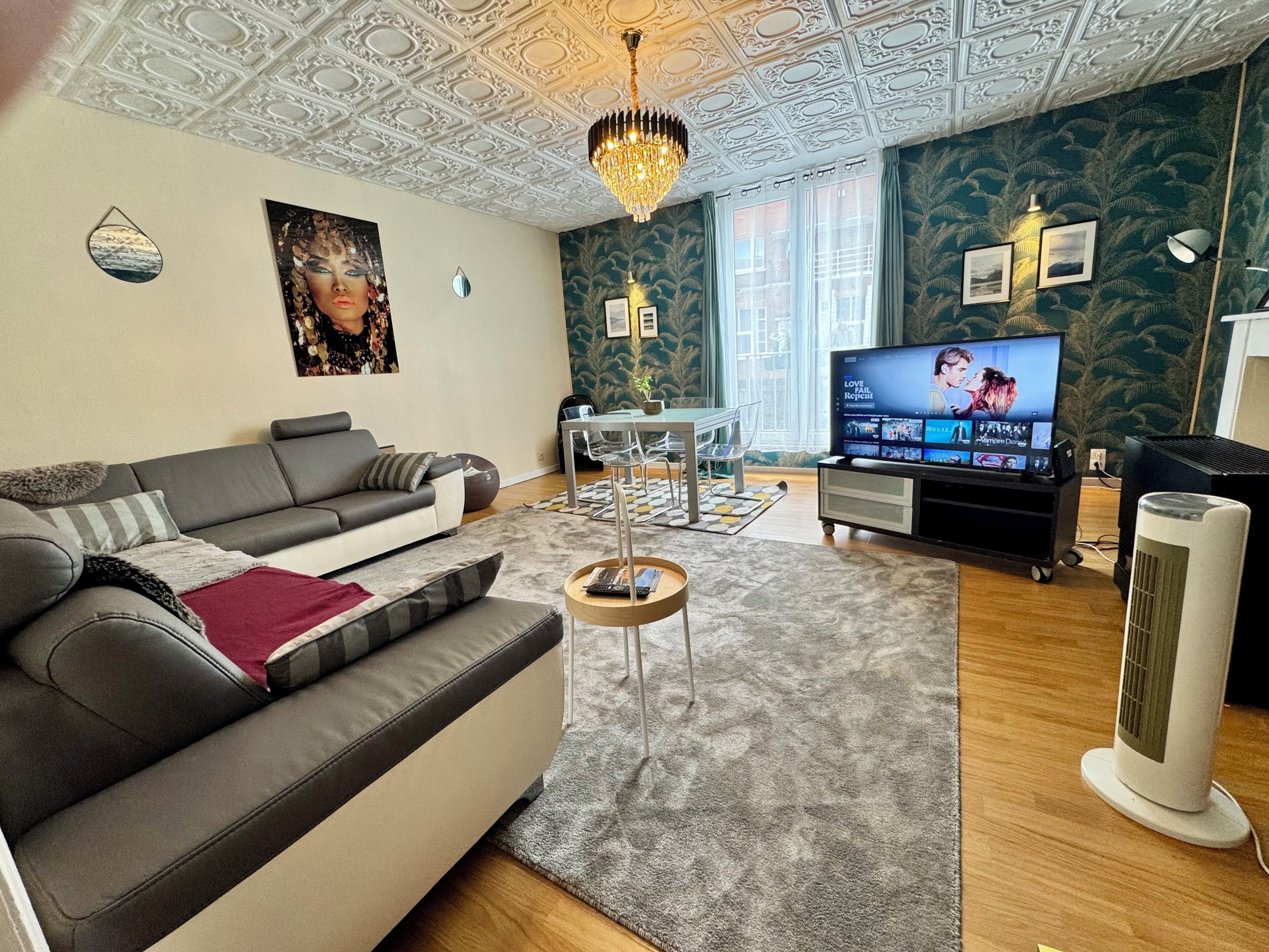 Un salon avec un canapé gris, une table basse, un téléviseur et un plafond décoratif.