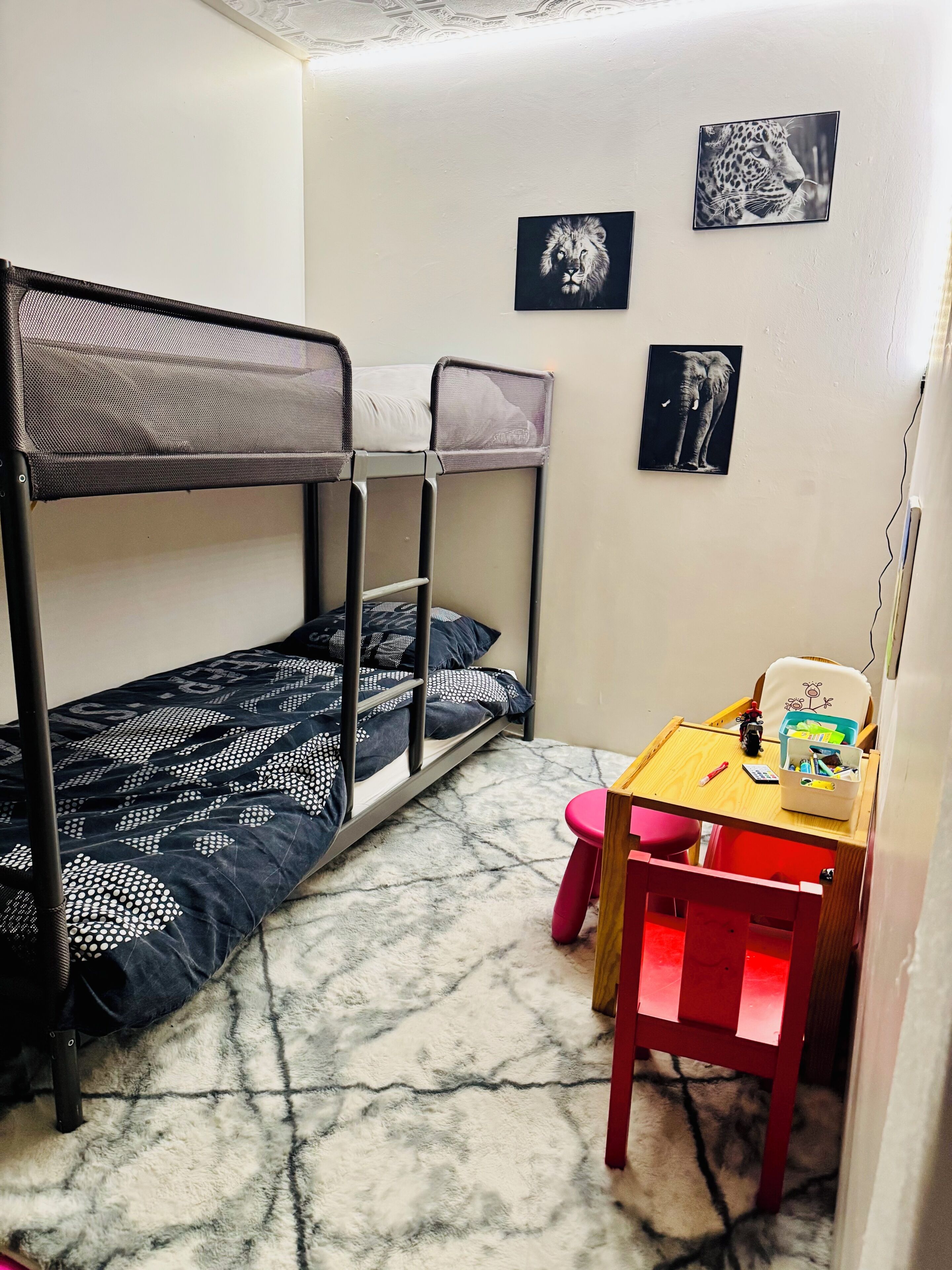 Un letto a castello con copriletto decorato, una scrivania con sedia e un quadro appeso al muro.