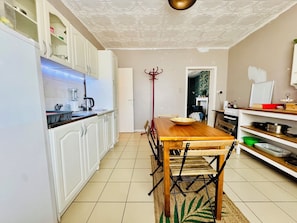 A kitchen with white cabinets, a wooden dining table, and a red coat rack. - Duplex next to the Casino de Namur (Namur)