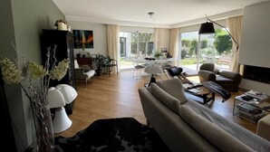 A modern living room with a sofa, coffee table, and dining area.
