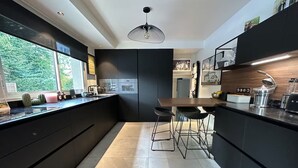 A modern kitchen with a central island, bar stools, a built-in oven, and a large window.