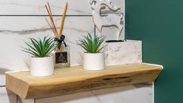 Uno scaffale con due piante in vaso, un diffusore e un oggetto decorativo.