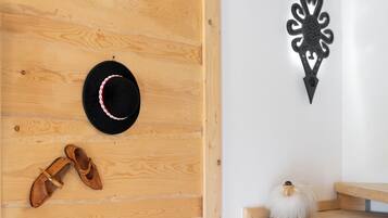 A wooden wall with a hat and shoes, a decorative wall piece, and a small white object on a shelf.