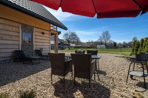 A wooden cabin with a gravel patio, outdoor seating, and a red umbrella. - RentPlanet Góralski Domek w Chochołowie (Chochołów)