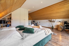 A bedroom with a bed, a wooden ceiling, a wardrobe, a chair, and a lamp. - RentPlanet Góralski Domek w Chochołowie (Chochołów)