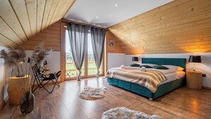 Un dormitorio con techo de madera, una cama con ropa de cama color turquesa, una silla, una lámpara y un florero con plantas secas.