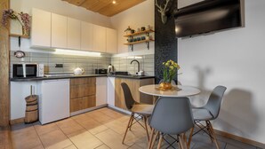 Una cocina moderna con armarios de madera, microondas, lavaplatos y un comedor con dos sillas.