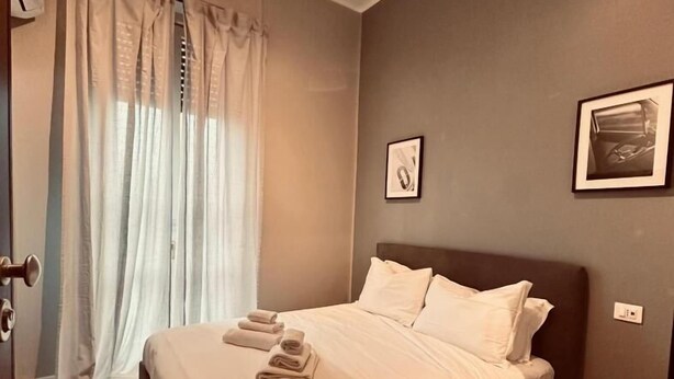 A bedroom with a bed, curtains, and two framed pictures on the wall. - HH Tortona (Tortona)