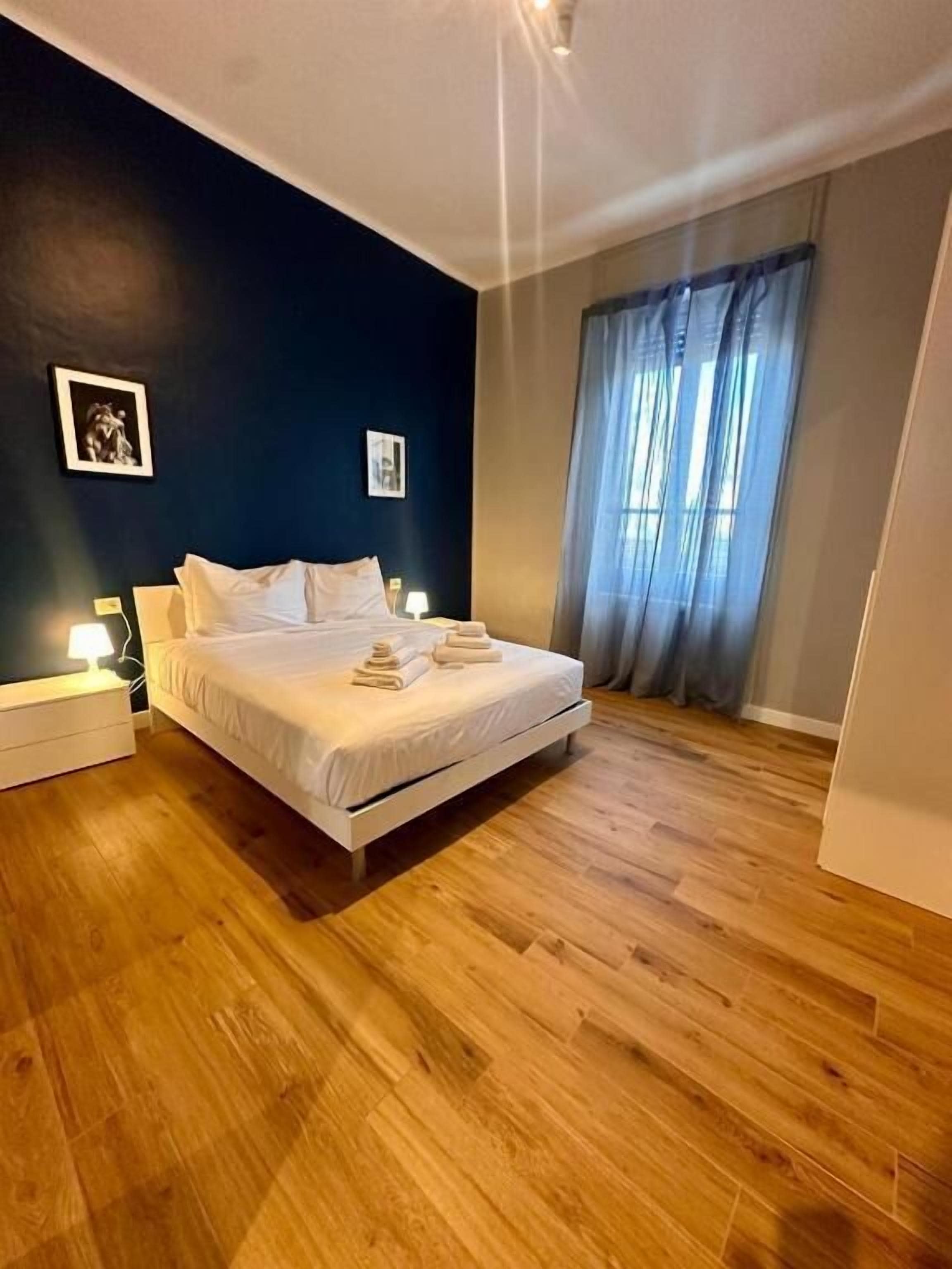 A bedroom with a bed, bedside tables, and a window with curtains.
