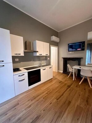 Una cocina moderna con armarios blancos, horno empotrado y comedor con mesa y sillas.