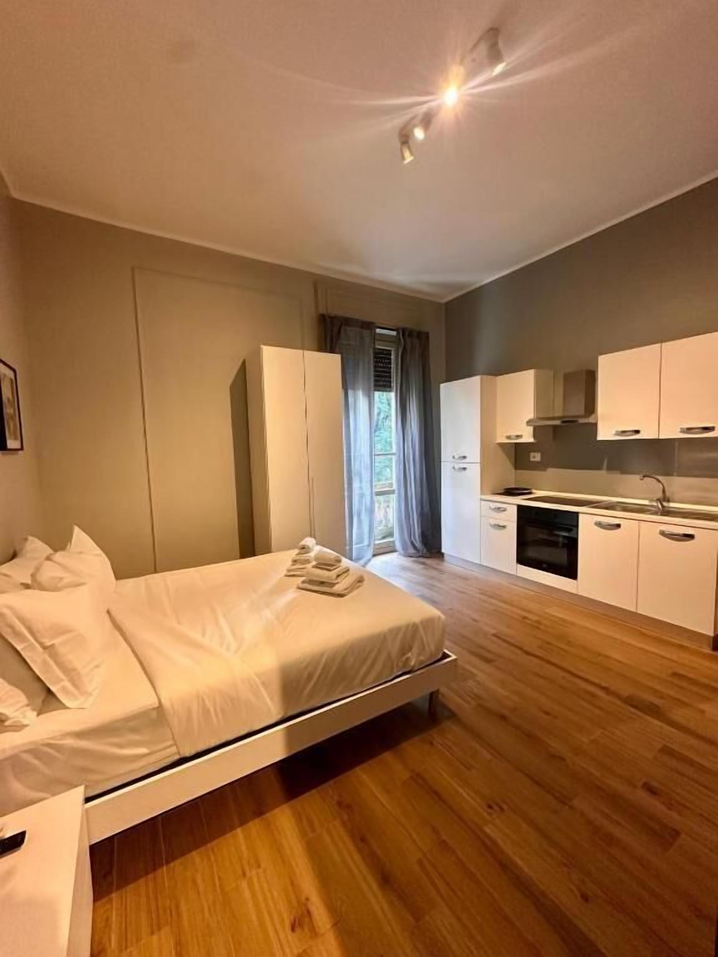 Een moderne slaapkamer met een bed, een klein nachtkastje en een raam met gordijnen.
