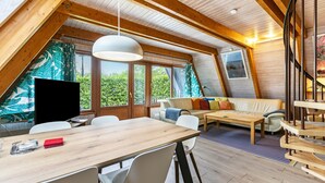 Un ampli loft modern i acollidor, amb sostre de fusta, taula de dinar, sofà i televisió.