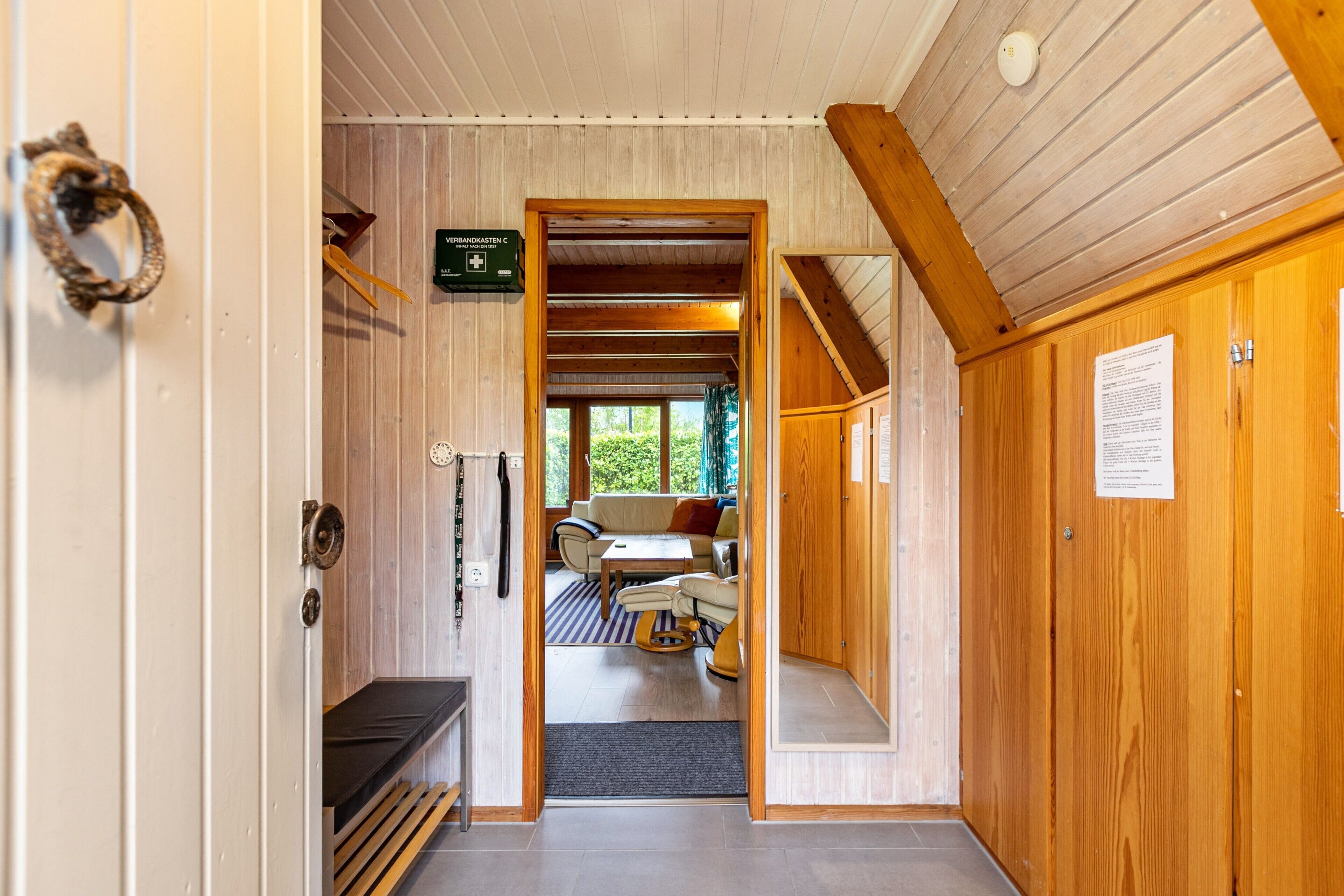 Interior de madera con sofá, mesa y vista por una puerta.