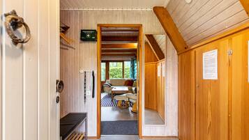 Interior de madera con sofá, mesa y vista por una puerta.