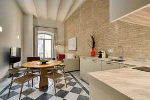 Una cocina moderna con piso a cuadros, una zona de comedor con mesa y sillas redondas, un sofá y una pared de ladrillo.