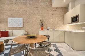 Een moderne keuken met een eethoek, met een bakstenen muur, een magnetron en een eettafel met stoelen.