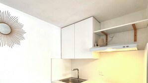 A modern kitchen with white cabinetry, a stainless steel sink, a built-in oven, and a trash bin. - Micro house by the sea (Le Barcarès)