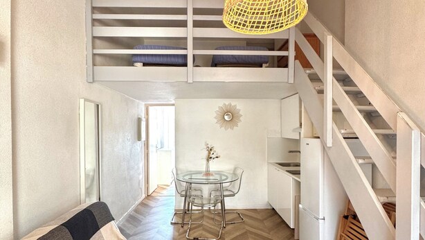 A loft-style room with a bed, a dining table, and a kitchen area. - Micro house by the sea (Le Barcarès)