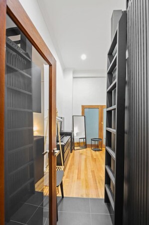 Un pasillo con una puerta de madera, un escritorio con una silla, una pizarra y estanterías llenas de libros.