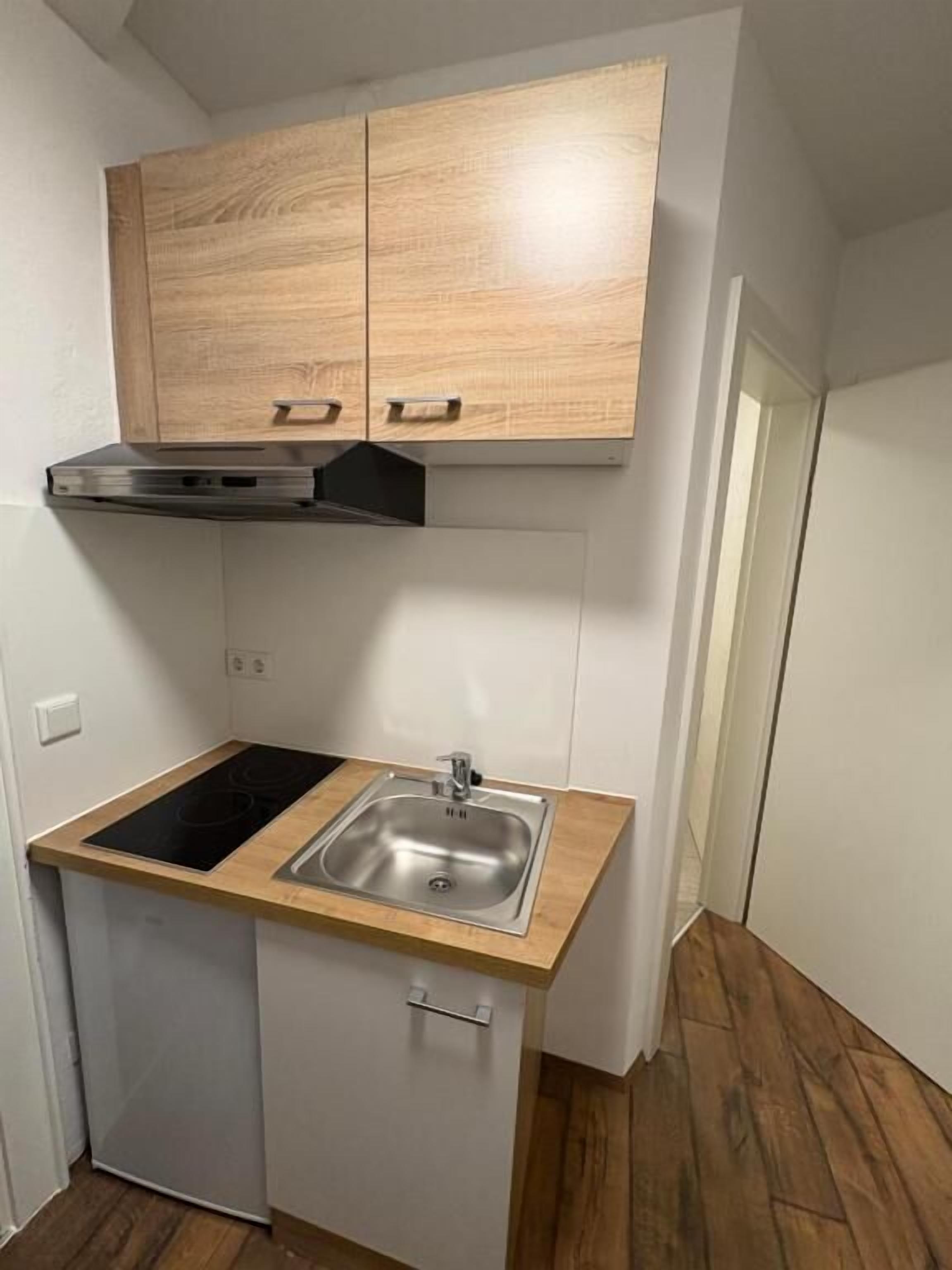 A compact kitchen with a built-in stove, a sink, and wooden cabinets.