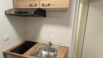 A compact kitchen with a built-in stove, a sink, and wooden cabinets.