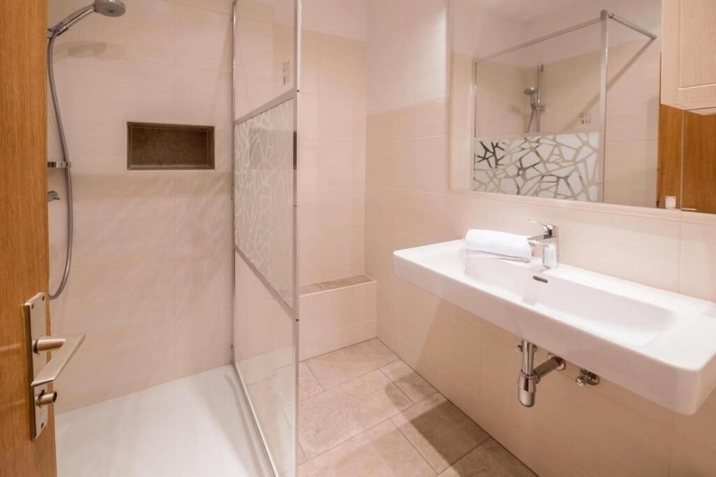 Un bagno con doccia, lavandino e specchio.