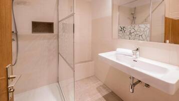 Un bagno con doccia, lavandino e specchio.