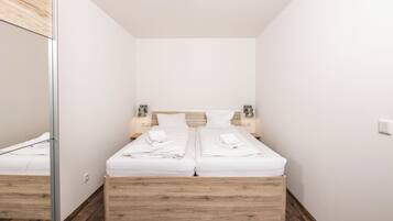 Ein modernes Schlafzimmer mit einem Bettgestell aus Holz, weißer Bettwäsche und Nachttischlampen.