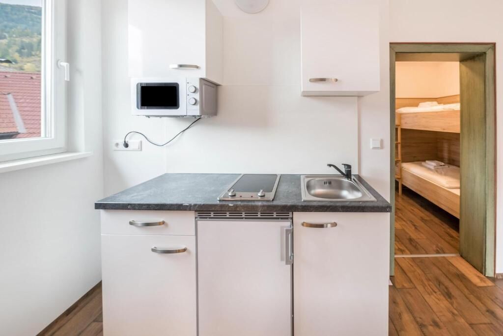 A compact kitchen with a microwave, a sink, and a window.
