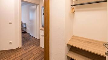 A hallway with wooden flooring, a white door, and a wooden bench with a towel rack.