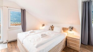 Un dormitorio con una cama grande, cabecera de madera, mesitas de noche y vistas al exterior.