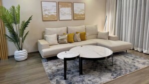 A modern living room with a sofa, a coffee table, a potted plant, and artwork on the wall. - Apartments at Abrish by Karibu Stays (Kampala)