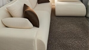 Un soggiorno moderno con un divano bianco, una poltrona coordinata e una pianta in vaso.