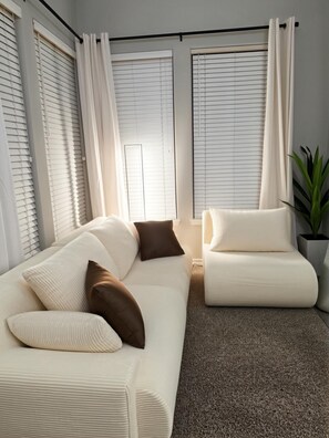 Una sala de estar moderna con un sofá blanco, un sillón a juego y una planta en maceta.