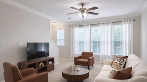 Ein Wohnzimmer mit Fernseher, zwei Sofas, einem Couchtisch und einem Deckenventilator.