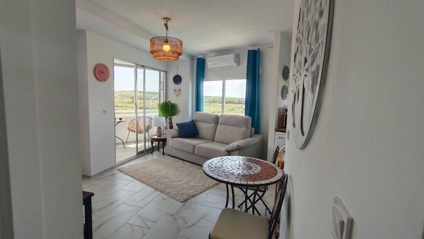 A living room with a sofa, a round table, and a view of the outdoors. - Bright one bedroom apartment in La Mata, Avenida Suiza. With pool. (La Mata)