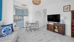 A living room with a sofa, a TV, a dining table with chairs, a kitchen in the background, and a ceiling light fixture. - Bright one bedroom apartment in La Mata, Avenida Suiza. With pool. (La Mata)