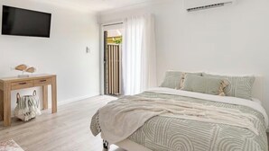 Ein Schlafzimmer mit Bett, Schreibtisch, Fernseher und Klimaanlage.