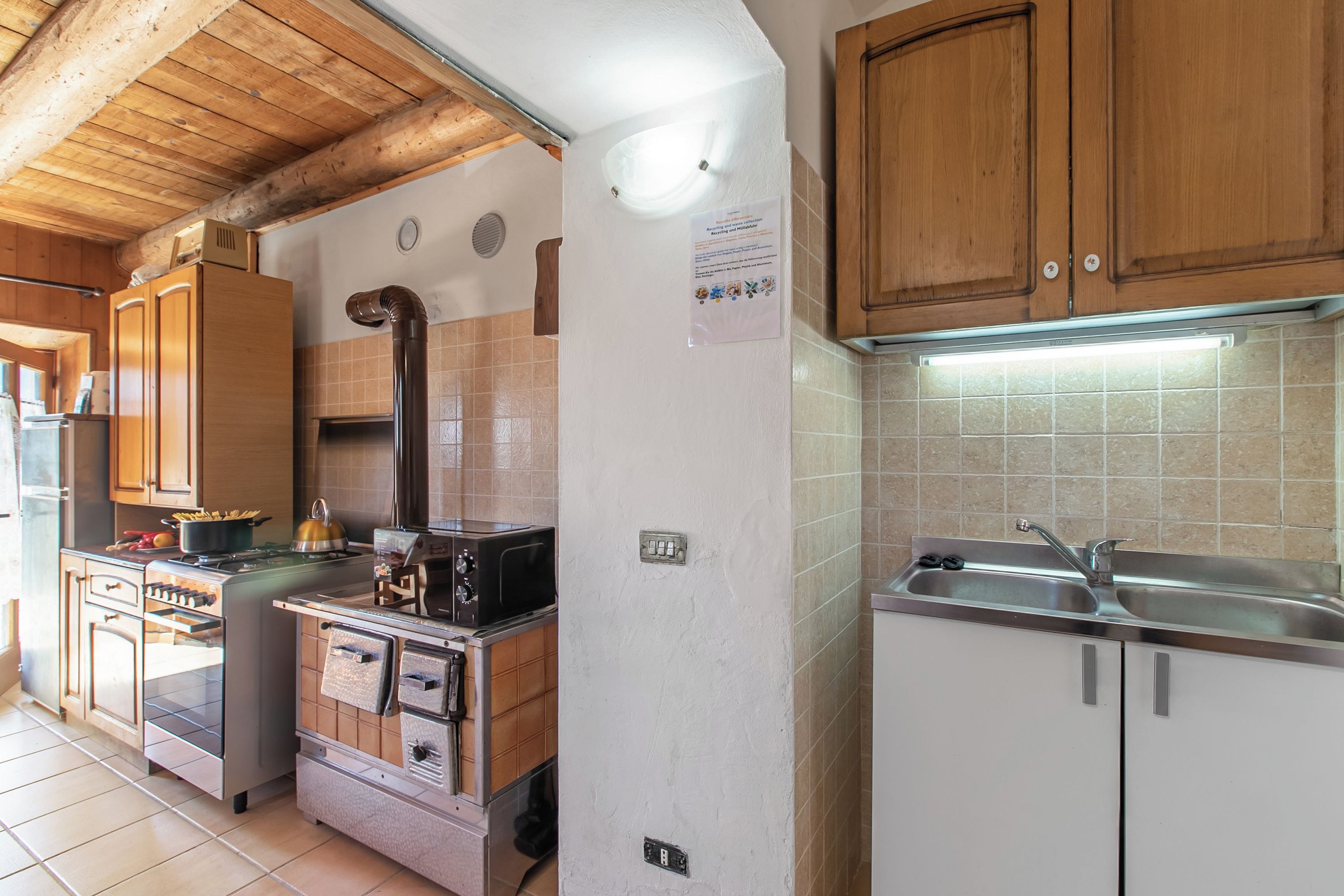 A kitchen with wooden cabinets, a stove, a microwave, and a sink.